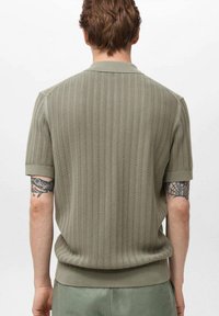 Kurzärmliges, geripptes Poloshirt in Olivgrün mit strukturiertem Muster und solidem Kragen. Die Rückansicht zeigt das figurbetonte Design und den Saum.