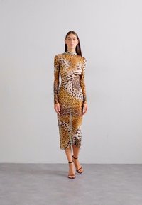 Leopard print long-sleeve dress with a high neck, form-fitting design, semi-sheer fabric, reaching mid-calf, paired with black ankle straps.