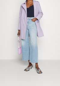 Fialový trenčkot, černý top, světle modré široké džíny, otevřené podpatky se zebrovým potiskem a malá levandulová kabelka s popruhem.