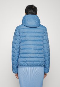 Jasnoniebieska pikowana kurtka puchowa z kapturem, z poziomymi przeszyciami i elastycznym obszyciem. Gładka faktura, lekka waga.