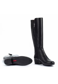 Stivali neri in pelle al ginocchio con una texture liscia, zip laterale e tacco basso a blocco. La suola in gomma presenta un motivo a tassello per una maggiore aderenza.