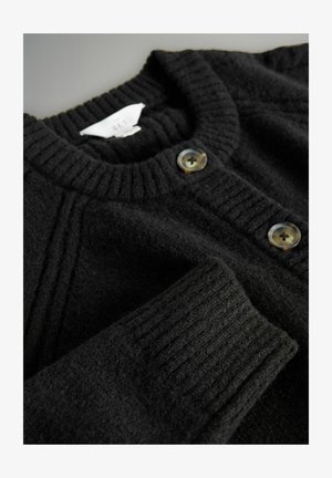 Cardigan in lana nera con colletto a coste, caratterizzato da due grandi bottoni rotondi e opachi sul davanti. Tessuto morbido e vestibilità leggermente ampia.
