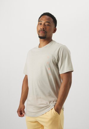 Light beige short-sleeve T-shirt featuring a textured design and a small orange "PUMA" logo on the left side.
