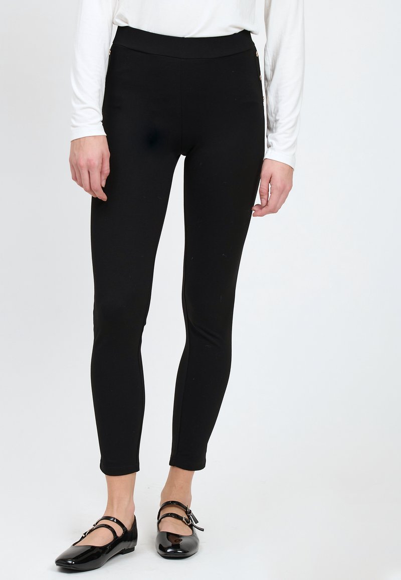 Zwarte leggings met een hoge tailleband en zijritsen. De stof is glad en rekbaar, ontworpen voor comfort en bewegingsgemak.