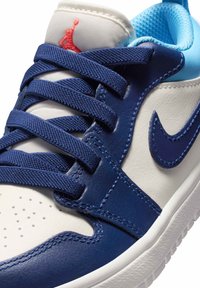 Niebiesko-białe tenisówki z granatową skórą, materiałowym językiem i teksturowaną siateczkową wyściółką. Posiadają ozdobne przeszycia oraz czerwone logo w pobliżu kołnierza.