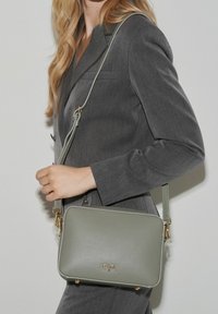 Borsa a tracolla in pelle grigia con dettagli in oro, forma rettangolare, superficie testurizzata e tracolla regolabile, complementare a un completo.