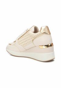 Zapatillas crema con parte superior de tejido, acentos metálicos dorados y una suela de cuña acolchada. Presenta un acabado texturizado y un diseño de cordones.