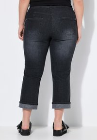 Jeans de mezclilla oscura recortados con dobladillo enrollado, que cuentan con dos bolsillos traseros y una textura suave, diseñados para una silueta ajustada.