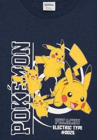 Sötétkék póló, amelyen több sárga Pikachu karakter található. A szöveg tartalmazza a "POKÉMON" és a "PIKACHU ELECTRIC TYPE #0025" feliratokat.