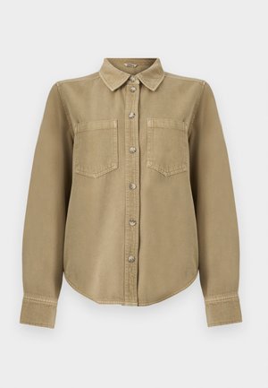 Camisa beige de manga larga con botones, dos bolsillos en el pecho y cuello clásico, mostrada sobre un fondo blanco uniforme.