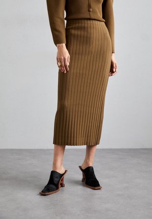 Brown ribbed knit midi skirt with a fitted waist and side slit, paired with black mules featuring a block heel and curved design.