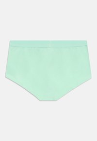 Helle grüne nahtlose Damenunterwäsche in Form von Slips mit einem breiten elastischen Bund auf einem schlichten Hintergrund.