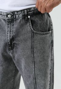 Grijze denim jeans met een verweerde afwerking, een rechte snit, standaardzakken en zichtbare stiksel details. Knopenluiting aan de taille.