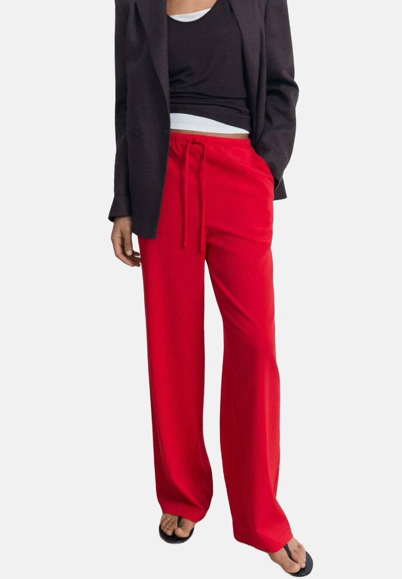 Rode, wijde broek met een trekkoord in de taille. Lichtgewicht stof met een gladde textuur. Gekocht met een zwart tanktop en blazer.