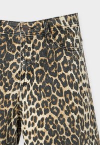 Jeans de mezclilla con estampado de leopardo en una combinación de patrones en negro y marrón, que cuentan con un clásico diseño de cinco bolsillos y cierre de botón metálico.