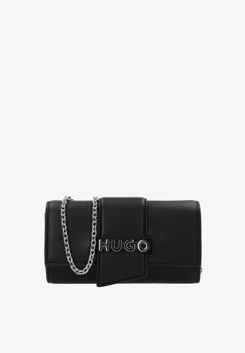 Cartera de cuero negro con un diseño plegable, correa de cadena plateada y un prominente logo "HUGO" plateado en la parte frontal. Textura suave con líneas limpias.