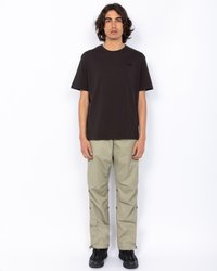 Czarny bawełniany t-shirt z okrągłym dekoltem, zestawiony z jasnobeżowymi spodniami cargo z bocznymi kieszeniami i zatrzaskami, noszony z czarnymi butami.