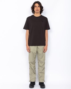 Czarny bawełniany t-shirt z okrągłym dekoltem, zestawiony z jasnobeżowymi spodniami cargo z bocznymi kieszeniami i zatrzaskami, noszony z czarnymi butami.