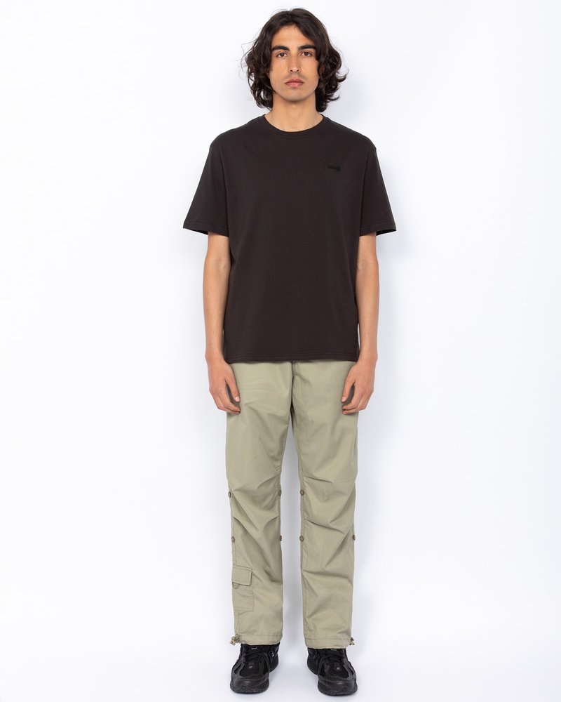 Czarny bawełniany t-shirt z okrągłym dekoltem, zestawiony z jasnobeżowymi spodniami cargo z bocznymi kieszeniami i zatrzaskami, noszony z czarnymi butami.