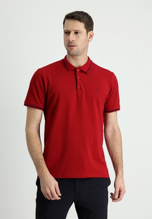 Camisa polo roja de algodón, con un cuello con ribete azul marino, tapeta de tres botones y mangas cortas. Logo simple bordado.