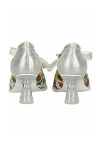 Zapatos de tacón alto blancos con estampado floral y acentos plateados, tacones transparentes y cinta de satén. Superficies texturizadas y diseño único.