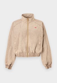 Μπεζ μπουφάν bomber με ψηλό γιακά, ολόκληρο φερμουάρ, ελαστικό τελείωμα, πλαϊνές τσέπες και διακριτική υφή. Διαθέτει μικρό κόκκινο λογότυπο στο στήθος.