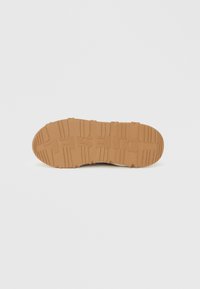 Λαστιχένια σόλα παπουτσιού με υφή και σχέδιο πέλματος. Διαθέτει ανοιχτό καφέ χρώμα και αναγλυφό λογότυπο. Λείες άκρες και ανθεκτικός σχεδιασμός.