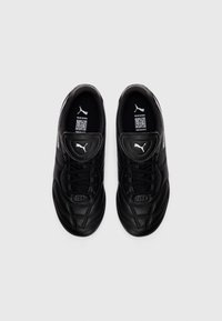Par de zapatos de fútbol de cuero negros Puma LIGA con cordones y lengua acolchada, vistos desde arriba sobre un fondo blanco.
