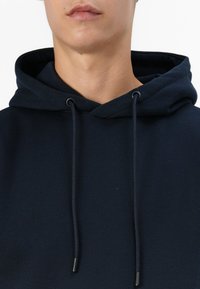 Navy blue hoodie with a drawstring, featuring a smooth texture and a relaxed fit. The fabric appears soft and thick around the neckline.