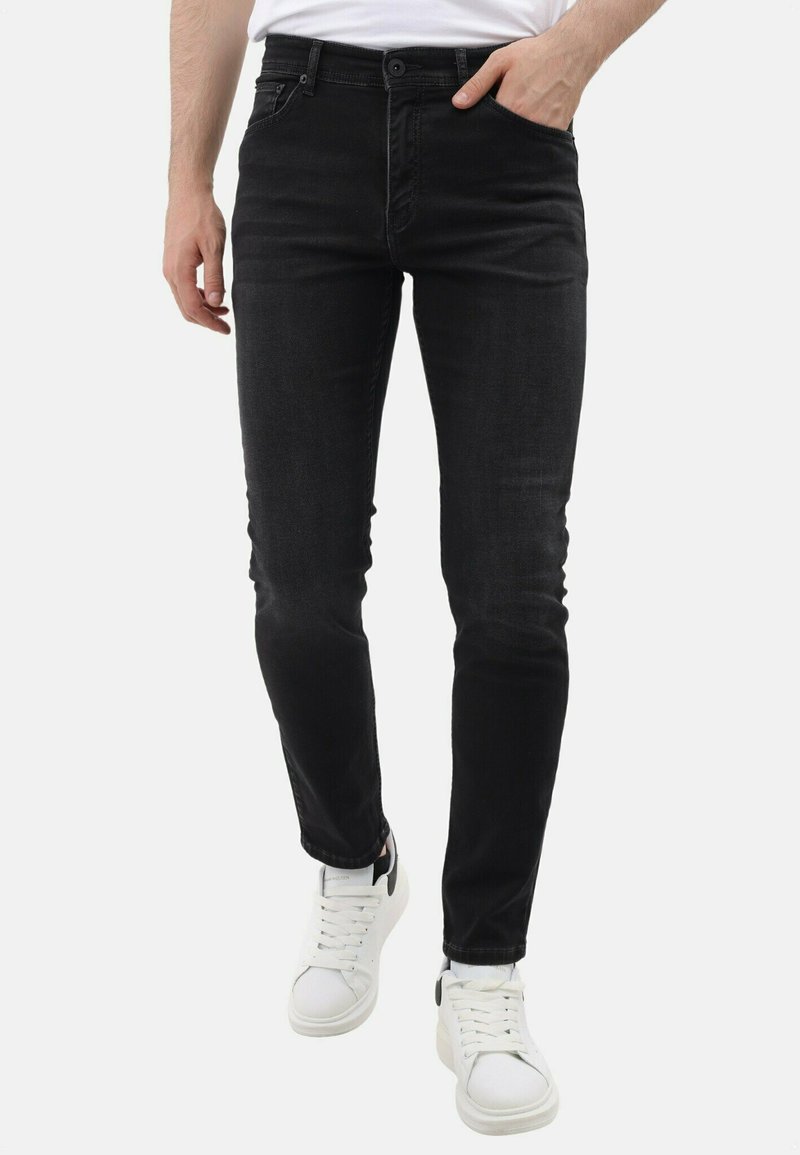 Zwarte denim skinny jeans met een zachte textuur, vijf zakken en een knoopsluiting. Gepaard met witte sneakers en een eenvoudig wit t-shirt.