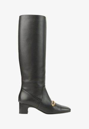 Botte haute en cuir noir avec un petit talon carré bas et un petit détail de boucle dorée sur le devant près de la cheville.