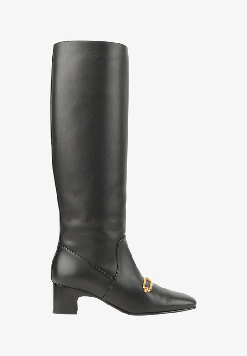 Botte haute en cuir noir avec un petit talon carré bas et un petit détail de boucle dorée sur le devant près de la cheville.