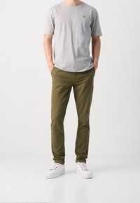 Grijze katoenen t-shirt met korte mouwen, gecombineerd met olijfgroene chinos en witte sneakers. Eenvoudig ontwerp, geen patronen of zichtbare hardware.
