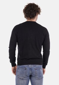 Suéter de algodón negro con cuello redondo, mangas largas y ribetes en el borde, visto desde la parte trasera sobre un fondo blanco.