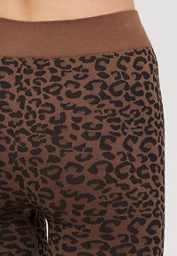 Smeđe tajice s crnim uzorkom leoparda, s rebrastim pojasom i teksturiranim materijalom za udobnost.