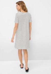 Robe à manches courtes rayée en blanc et noir. Tissu doux, encolure ronde, longueur genou, coupe décontractée et légèrement évasée.