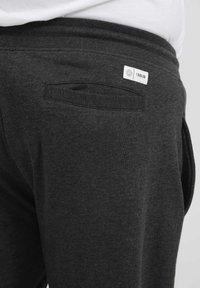 Dunkelgraue Sweatpants mit weichem Material, einer Gesäßtasche und einem kleinen weißen Markenetikett in der Nähe des Bundes.