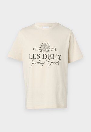 Cream-colored cotton t-shirt featuring a circular logo with laurel, text "LES DEUX Sporting Goods," and established date 2011 in black.