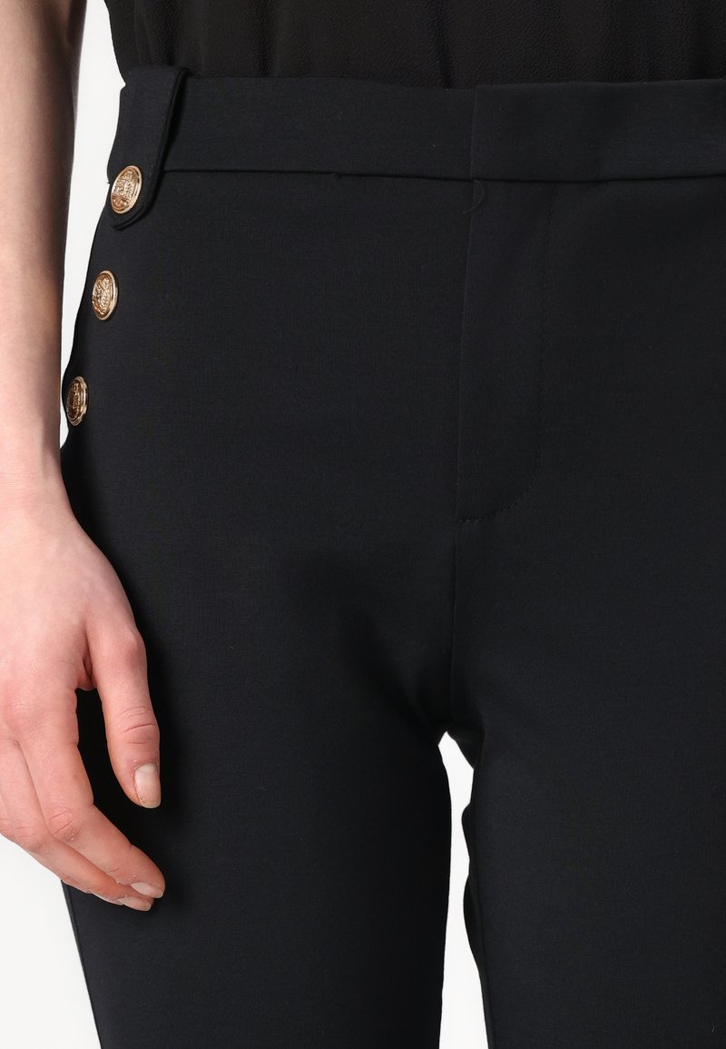 Schwarze maßgeschneiderte Hose mit glatter Textur, seitlichen Eingrifftaschen und dekorativen goldenen Knöpfen auf der linken Seite des Bundes.