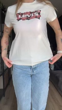 Bijela majica s cvjetnim logom "Levi's" na crnoj podlozi. Ima kratke rukave i uski siluet.