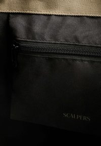 Bolsa de tela negra con cremallera, con una parte superior de lona en tono marrón claro. El logo "SCALPERS" está impreso en gris claro en un lado.