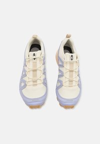 Sport shoes with a cream mesh upper, light purple accents, and beige laces. Features a textured sole with rubber traction patterns.