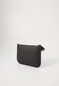 Μαύρη δερμάτινη θήκη με φερμουάρ σε χρυσό χρώμα και μαύρο κρόσσι, που στέκεται σε λευκό φόντο.