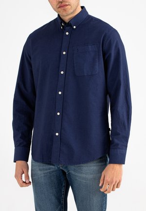Navy long-sleeve shirt with a button-down collar, chest pocket, and white buttons. Fabric appears smooth with a slight sheen.