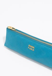 Funda de lápices color turquesa hecha de tejido suave. Cuenta con un cierre dorado y un logo en relieve "BIMBA Y LOLA" en el lateral. Forma rectangular.