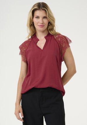 Red blouse with lace short sleeves, V-neck design, soft texture, relaxed fit, paired with black trousers. No visible patterns or hardware.
