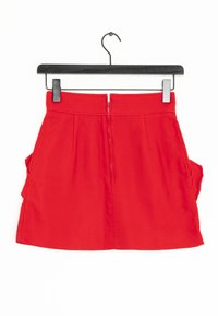 Rode katoenen rok met een rechte snit, rits aan de achterkant en zijzakken. Zachte textuur, minimale stikseldetails en geen zichtbare patronen.