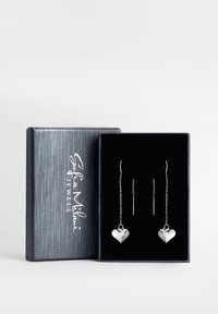 Silberne, herzförmige, hängende Ohrringe in einer mit schwarzem Samt ausgekleideten Geschenkbox mit einer strukturierten silbernen Außenseite. Lange dünne Haken und Ketten.