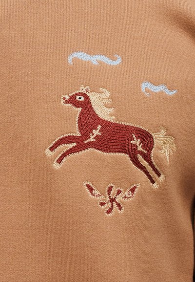 Κέντημα κόκκινου αλόγου με μπεζ χαίτη και ουρά, περιβαλλόμενο από μπλε σύννεφο-σχήματα και μικρό ανθικό σχέδιο σε ταμπά ύφασμα.