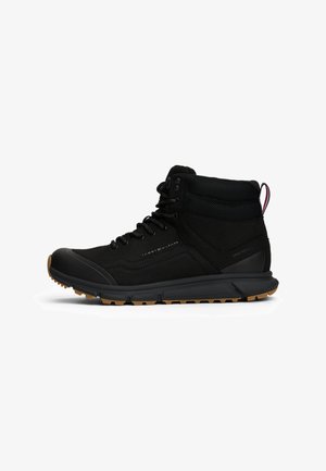 Schwarze Mid-Top-Stiefel mit einem Obermaterial aus Wildleder und Mesh, einer Gummikappe an der Zehenpartie und einer strukturierten Gummisohle für besseren Halt. Schnürsenkel und Logodetails sichtbar.